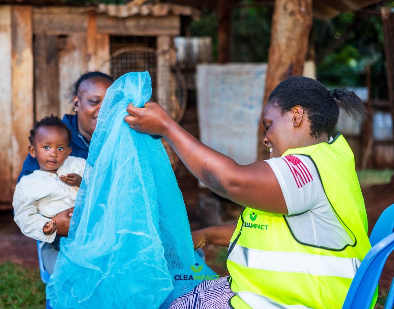 A mother holds her baby steady while two community health workers treat the child at a rural health post.